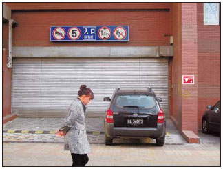 A resident passes the entrance of the closed parking building in Wangjing. 