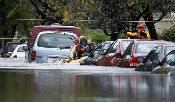 Emergency water rescue crew members ferry hotel guests from their hotel after heavy rains and flooding trapped guests staying at a hotel in San Diego, California Dec 22, 2010. [China Daily/Agencies] 