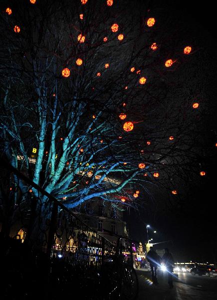 People walk past a lighted Christmas tree in downtown Geneva, Switzerland, Dec. 23, 2010. The whole city is lit up to greet the upcoming Christmas. [Xinhua]