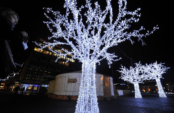 A tourist takes photos of a lighted tree in downtown Geneva, Switzerland, Dec. 23, 2010. The whole city is lit up to greet the upcoming Christmas. [Xinhua]
