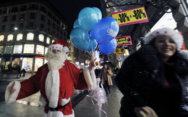 A salesman dressed as Santa Claus prepares to give out balloons to children on a shopping street in downtown Geneva, Switzerland, Dec. 23, 2010. The whole city is lit up to greet the upcoming Christmas. [Xinhua] 