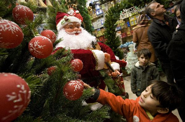 An Iranian child looks at a Christmas tree in a Christmas market in Tehran, capital of Iran, Dec. 23, 2010. More than 200,000 Iranian Christians live in Iran. [Xinhua]