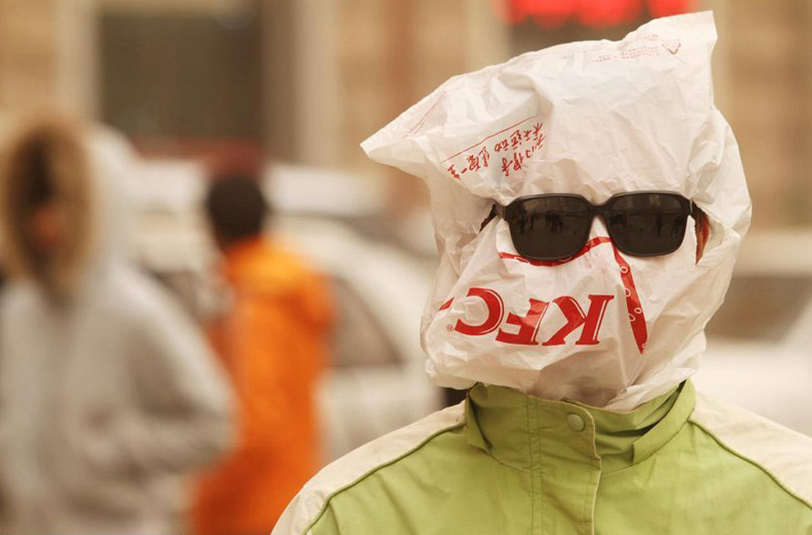 A pedestrian covers his face with a plastic bag against the sandstorm on March 22, 2010 in Beijing, China. Tons of sand carried by winds of up to 100 km/h has affected more than 270 million people in 16 provinces since Friday, covering about 2 million sq km. [Chinanews.com.cn]