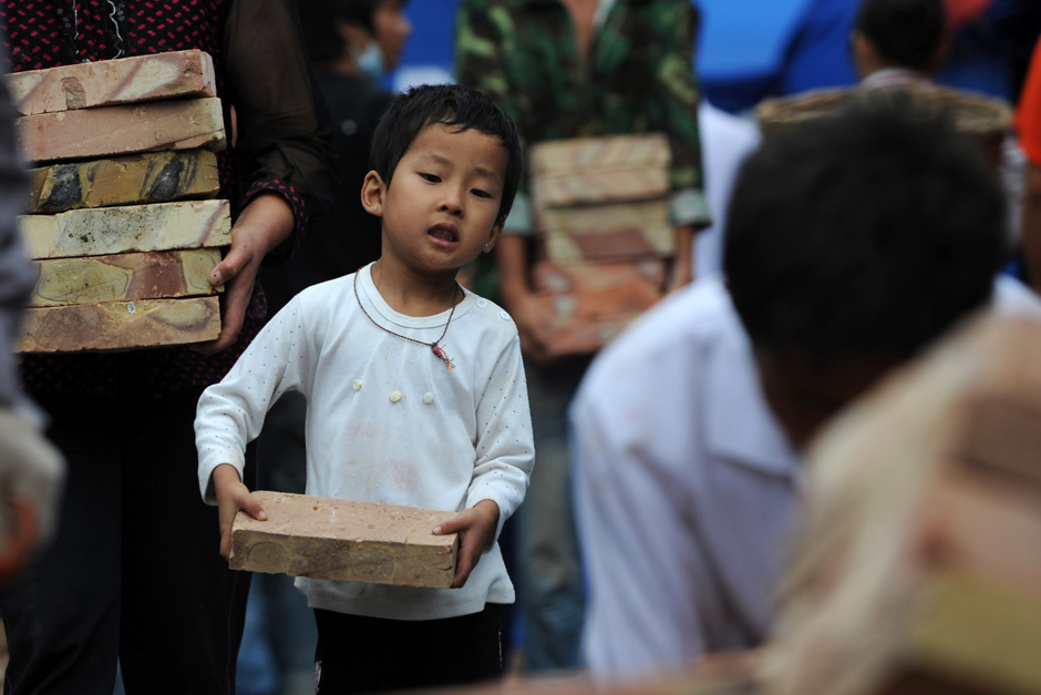 A 4-year-old volunteer is seen to give help in landslide-hit area Zhouqu on August, 13, 2010. [Xinhua]