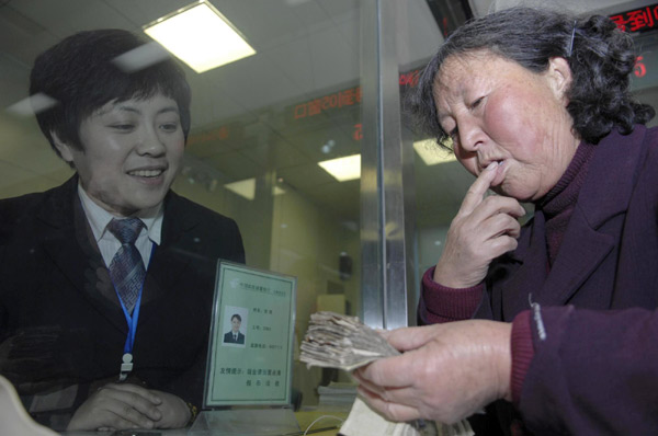 Sanitary worker Li Yukun, 64, counts her money before donating to a victim of the 2008 Wenchuan earthquake, at a post office in Wendeng city, East China's Shandong province, Dec 22, 2010. [Photo/Xinhua]