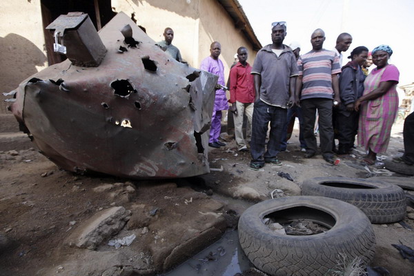 People look at a burnt area after an explosion in Nigeria&apos;s central city of Jos in this December 25, 2010 picture. [China Daily/Agencies] 