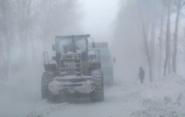 Snow plows work on the snow-covered road from Yilan to Boli in NE China&apos;s Heilongjiang province Dec 26, 2010. After a heavy snowfall, more than 700 vehicles and 1,000 people were stuck on the highway from Harbin to Tongjiang, and the road from Yilan to Boli in Northeast China&apos;s Heilongjiang province. [Xinhua]