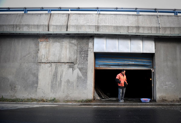 Migrant worker Tong Jinping waits for his colleague at the door of their residence under an overpass, in Hefei, Dec 26, 2010. [Photo/Xinhua]