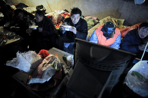 Migrant workers watch TV during lunchtime, Dec 24, 2010. [Photo/Xinhua]
