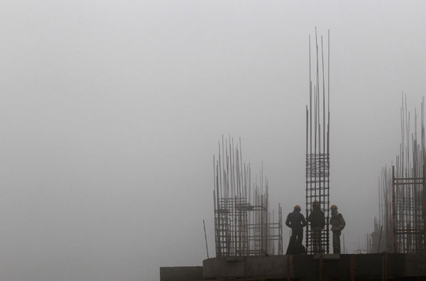 Labourers work at a construction site amid heavy fog near the airport in New Delhi Dec 27, 2010. 