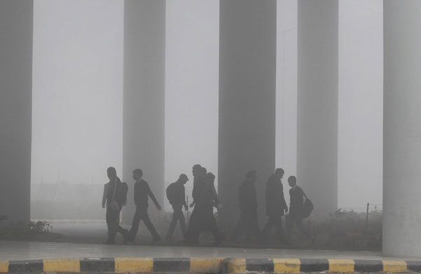 Airport staff walk towards the main terminal amid heavy fog in New Delhi Dec 27, 2010. [China Daily/Agencies] 