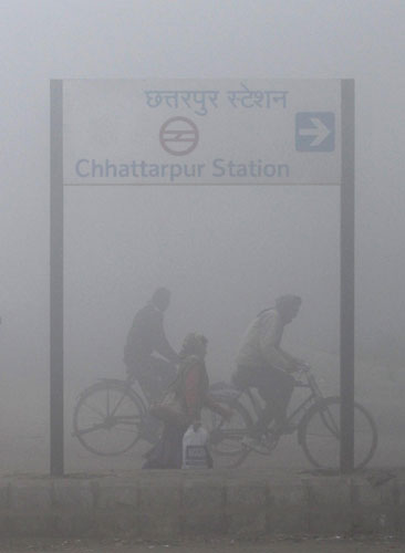 People ride bicycles on a foggy morning in New Delhi Dec 27, 2010. [China Daily/Agencies] 