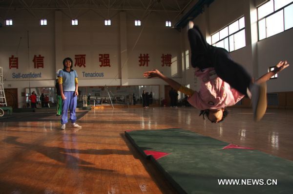 Fifteen-year-old Eint Chaw Chaw Thu (L) from Myanmar wathches twelve-year-old Nay Chi Su Su Lat practising somersaults at Wuqiao acrobatic art school in Wuqiao County, north China's Hebei Province, Dec. 23, 2010. 