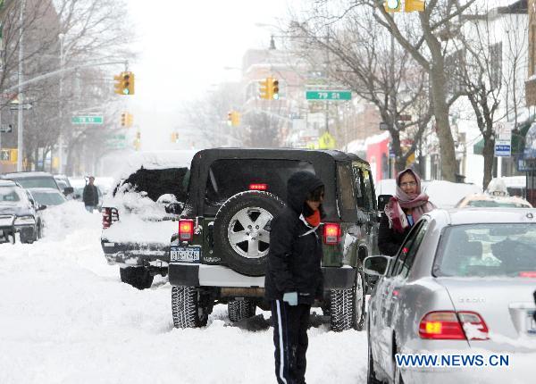 People look at a stranded car after a blizzard in the New York City borough of Queens on Dec. 27, 2010. 