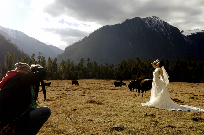 A bride poses for wedding photos at a scenery spot in Nyingchi, southwest China&apos;s Tibet Autonomous Region, Dec. 24, 2010. A total of ten pairs of newly married couples who were selected from thousands of candidates nation wide took part in a group wedding in Tibet recently. [Xinhua] 