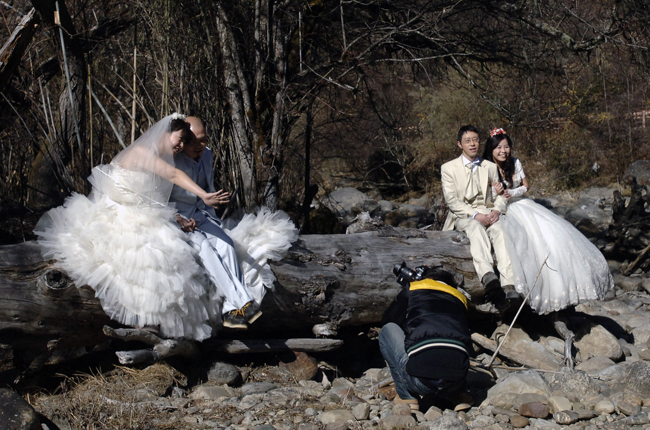 Newlyweds pose for their wedding photos at a scenery spot in Nyingchi, southwest China&apos;s Tibet Autonomous Region, Dec. 24, 2010. A total of ten pairs of newly married couples who were selected from thousands of candidates nation wide took part in a group wedding in Tibet recently. [Xinhua]