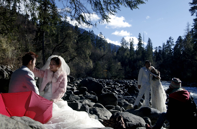 Newlyweds pose for their wedding photos at a scenery spot in Nyingchi, southwest China&apos;s Tibet Autonomous Region, Dec. 24, 2010. A total of ten pairs of newly married couples who were selected from thousands of candidates nation wide took part in a group wedding in Tibet recently. [Xinhua]