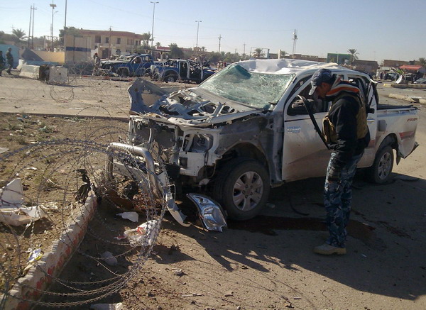 A policeman inspects a damaged vehicle at the site of a bomb attack in Ramadi, 100 km (60 miles) west of Baghdad, Dec 27, 2010. Twin suicide bombings rocked a government compound in Iraq&apos;s western city Ramadi on Monday, with a police source saying more than 17 people had been killed. [China Daily/Agencies] 