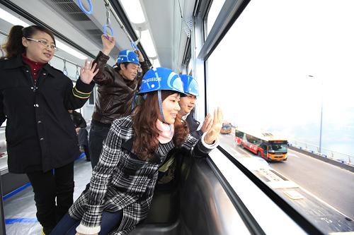 People wave hands on a trial train of Chongqing Subway Line No.3 in southwest China&apos;s Chongqing Municipality, Dec. 28, 2010. The subway line, with the highest speed of 75km per hour, started its trial run on Tuesday. It will be formally put into operation in June of next year. [Xinhua]