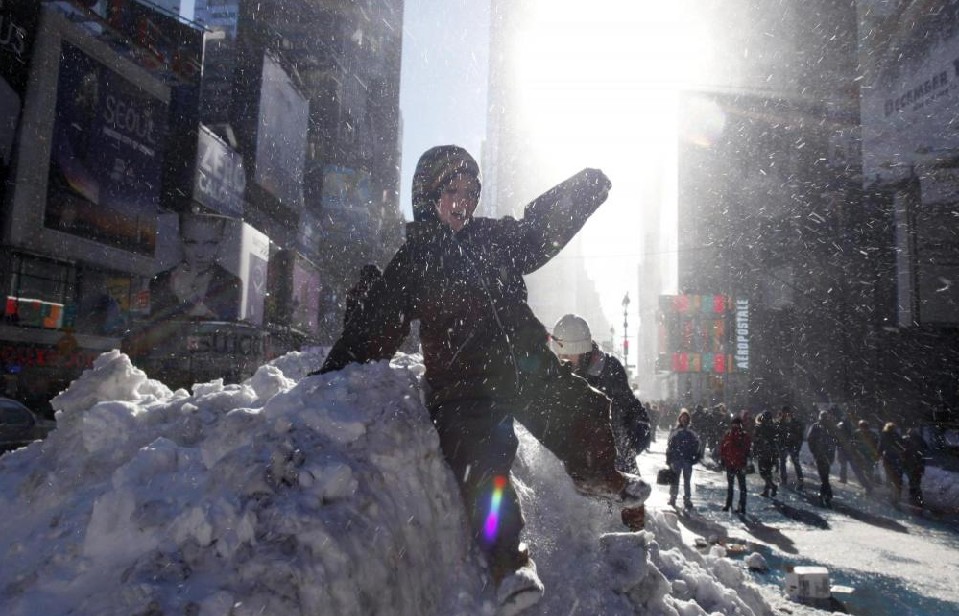  Blowing snow swirls around a young boy sliding off a mound of snow in Times Square in New York, Dec 27, 2010. [China Daily/Agencies]