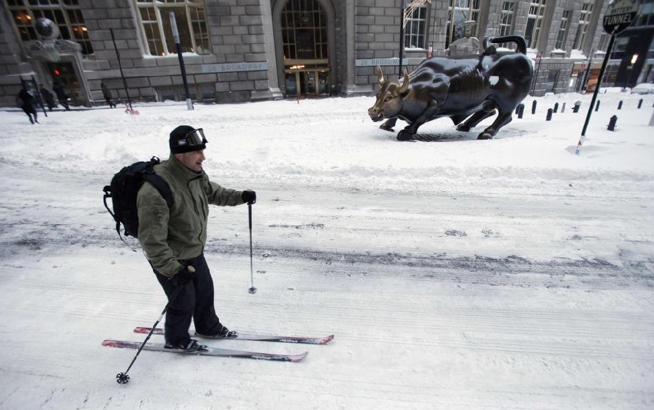 A man skis past a bronze statue of a charging bull on Wall St. after a snow storm in New York Dec 27, 2010. [China Daily/Agencies]