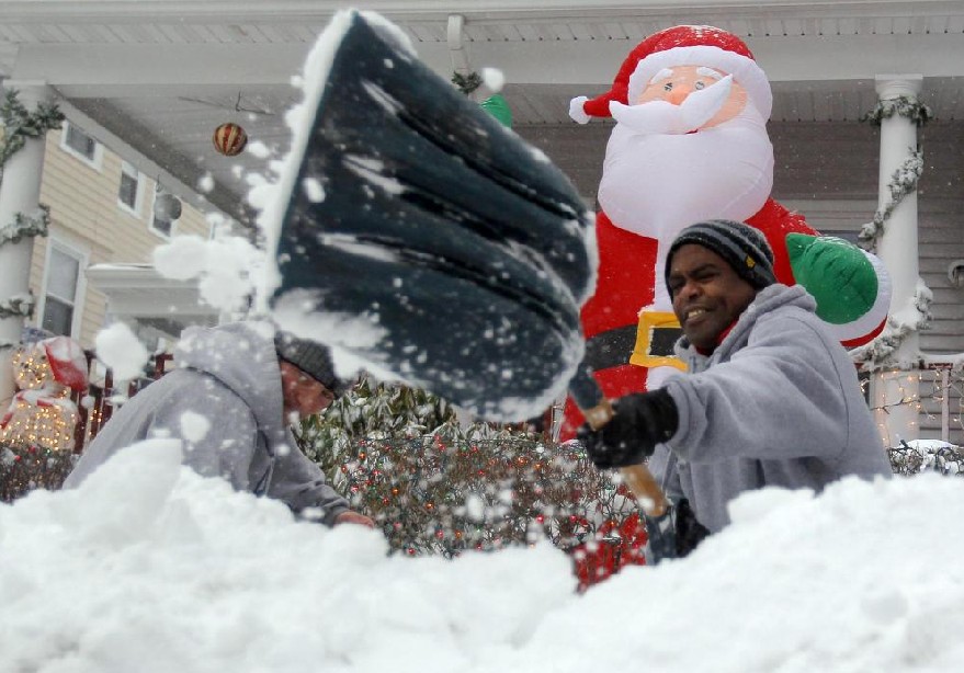 Shawn Keefe (L) and Abdi Yusuf clear snow from the front of a residence during a snowstorm in Somerville, Massachusetts Dec 27, 2010. [China Daily/Agencies]