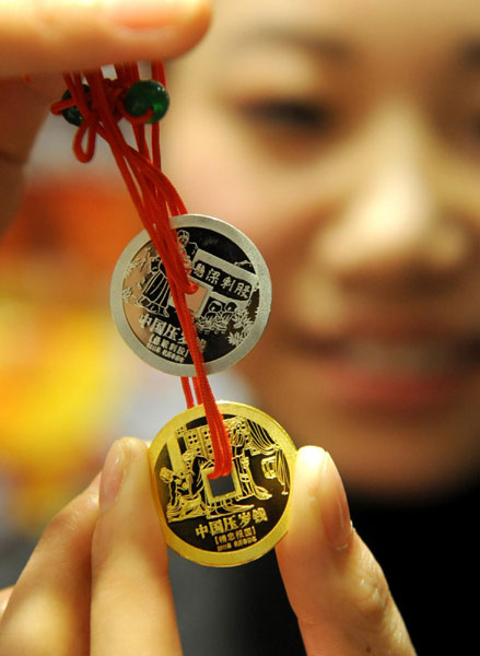 Newly released coins are shown at Caibai Mall in Beijing, Dec 28, 2010. The new gift money has two coins, one golden and one silver, which are imprinted with characters from two traditional Chinese stories. Every year since 2008, the art department center of the National Museum of China has been supervising the release of the traditional gift money. [Xinhua]