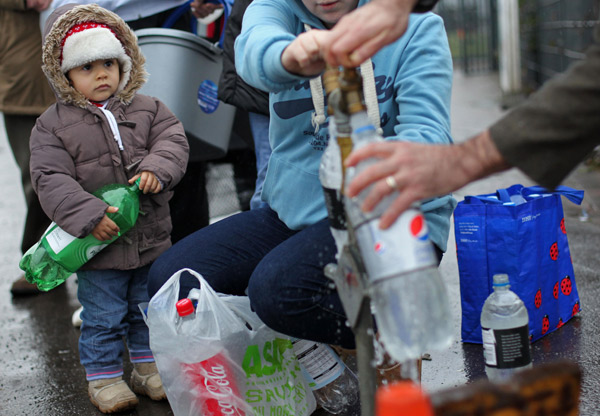 A child, with an empty bottle, watches as people queue to use an outside tap in Belfast, Northern Ireland on Dec. 29, 2010. 