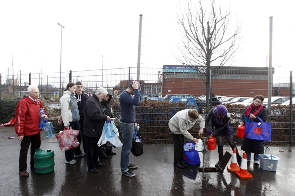 People queue to fill containers with water from a pipe on the Boucher road in Belfast, Northern Ireland Dec 29, 2010. [China Daily/Agencies]