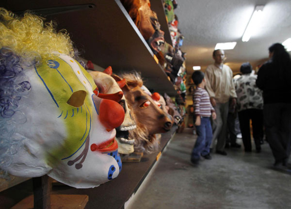 Customers shop at a mask store in Quito Dec 29, 2010. Ecuadoreans burn puppets and wear masks during end of year celebrations. [China Daily/Agencies] 