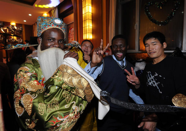 Wearing Peking opera costumes, a student from Togo (L) takes pictures with his friend at the party for Christmas and New Year at Inner Mongolia University of Technology in Hohhot, capital city of north China's Inner Mongolia Autonomous Region on Dec. 23, 2010. [Xinhua photo] 