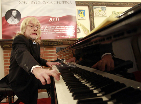 Pianist Stanislaw Deja stretches to play on the Stolemowi Klawer, which is in contention for the title of the world&apos;s biggest concert piano, during an event to mark the end of Chopin Year at a museum in Shymbark, northern Poland Dec 30, 2010. [China Daily/Agencies]