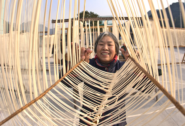 A woman dries handmade noodles in Majian Township of Zhuji City, east China&apos;s Zhejiang Province, Dec. 30, 2010. A handmade noodle making contest was held here on Thursday. The handmade noodles of Majian Township are famous for the length. Long noodles symbolize longevity in Chinese tradition. [Xinhua]