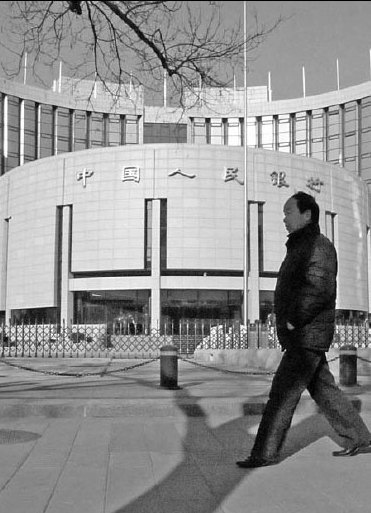A pedestrian passes the People's Bank of China. The central bank has raised the benchmark lending rate twice since mid-October. [China Daily]