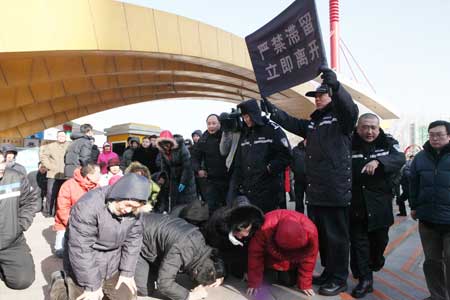 A policeman holds a banner saying, 'Lingering prohibited. Leave immediately,' as they try to disperse petitioners gathered Thursday at Beijing's Chaoyang Park. 