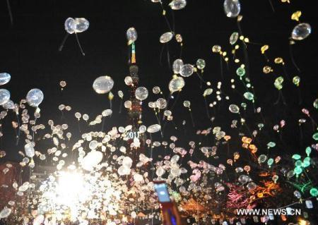 Girls wait to release the balloons during the New Year celebrations at the Zojoji temple in Tokyo, Japan, Dec. 31, 2010. [Xinhua/Ji Chunpeng]