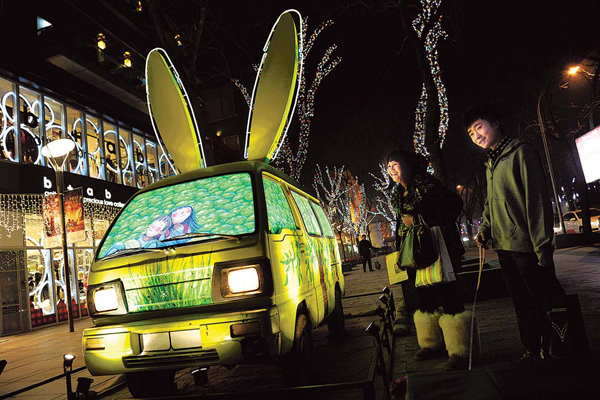 People check out a van decorated with two long ears and painted with fairy tale figures in Sanlitun, Beijing, on Dec 22, 2010. [Photo/China Daily] 