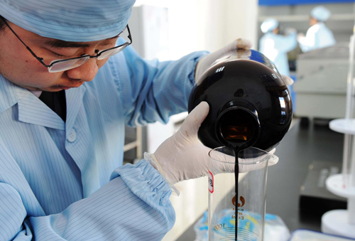 A worker from Mohe's entry-exit inspection and quarantine bureau samples a bottle of oil to monitor its quality at a plant in Mohe county, northeast China's Heilongjiang province, Jan 1, 2011. [Xinhua]