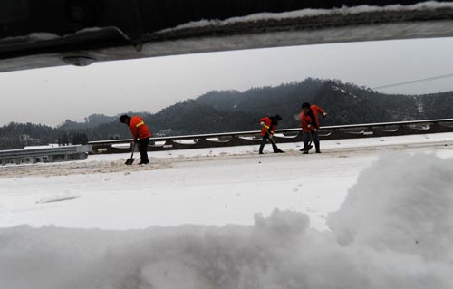 Road administration workers clear the ice covered on the Changde-Jishou Highway in Central China&apos;s Hunan province, Jan 3, 2011. Nearly 10,000 workers and officials have been working around the clock since Saturday to keep traffic moving on the icy expressways in Hunan. [Xinhua] 