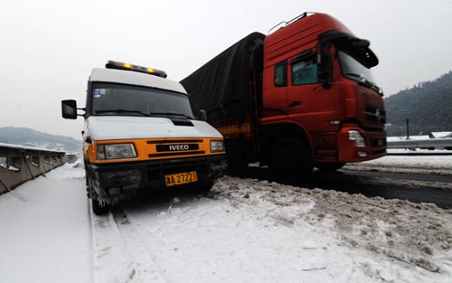 A truck runs beside a van belonging to the road administration on the Changde-Jishou Highway in Central China&apos;s Hunan province, Jan 3, 2011. Nearly 10,000 workers and officials have been working around the clock since Saturday to keep traffic moving on the icy expressways in Hunan. [Xinhua]