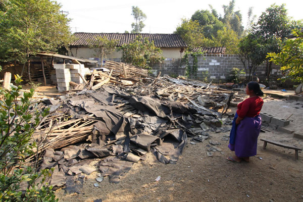 A pregnant woman looks at her damaged house in Yingjiang county, Yunnan province on Jan 3, 2011. [Xinhua] 