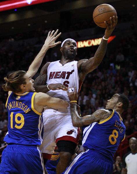 Miami Heat's LeBron James (C) shoots over Golden State Warriors' Lou Amundson (L) and Monta Ellis during third quarter NBA basketball action in Miami January 1, 2011. (Xinhua/Reuters Photo)