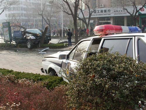 A damaged police car stands meters away from a crashed vehicle shortly after a gunfight in Tai&apos;an, East China&apos;s Shandong province, Jan 4, 2011. 