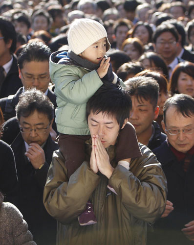 A boy copies his father praying at the Kanda Myojin shrine in Tokyo Jan 4, 2011, on the first business day of the year. [China Daily/Agencies]