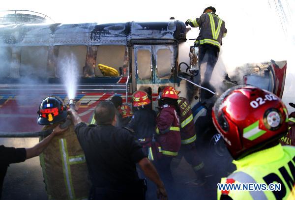 Firefighters extinguish a burning bus in Guatemala City, Guatemala&apos;s capital, on Jan. 3, 2011. Authorities informed that at least 5 people traveling on the bus were burned to death, and 16 others suffered severe burns after a bomb thrown by an unidentified person hit the vehicle. [Xinhua]