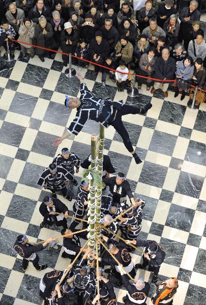 A member of the Edo Civilian Firefighters&apos; Association performs on the top of a bamboo ladder following the New Year&apos;s holiday at Mitsukoshi department store in Tokyo on January 4, 2011. [Xinhua/AFP] 