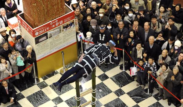 A member of the Edo Civilian Firefighters&apos; Association performs on the top of a bamboo ladder following the New Year&apos;s holiday at Mitsukoshi department store in Tokyo on January 4, 2011. [Xinhua/AFP]