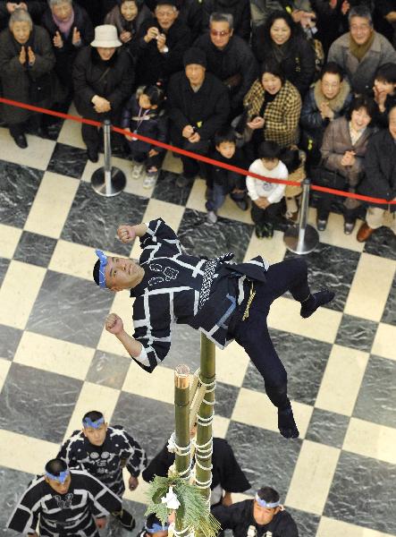 A member of the Edo Civilian Firefighters&apos; Association performs on the top of a bamboo ladder following the New Year&apos;s holiday at Mitsukoshi department store in Tokyo on January 4, 2011. [Xinhua/AFP]