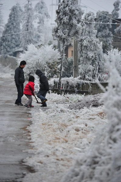 People shovel snow by the road in Kaiyang county, Southwest China&apos;s Guizhou province, Jan 4, 2011. 