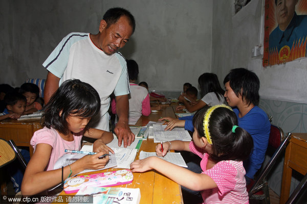 Deng Weixing, a meat retailer who runs a 'home for left-behind students,' helps them study at the home in Shitai township of Yingde city, South China's Guangdong province.